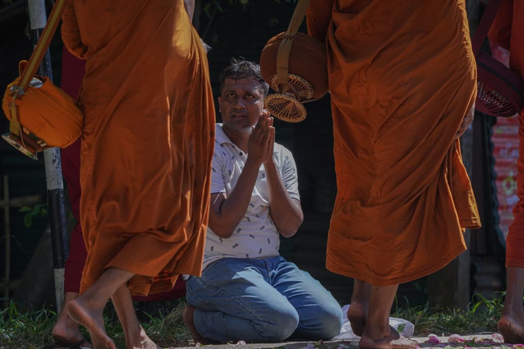 พระสงฆ์ถือบาตรเดินบิณฑบาตตอนเช้าบนทางเท้า