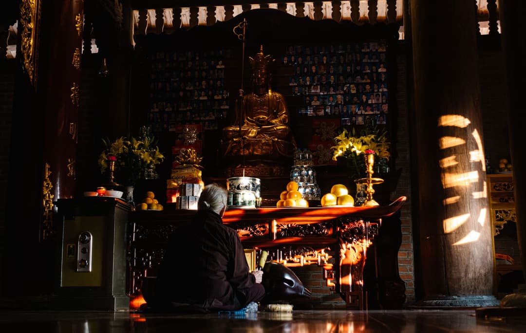 โต๊ะหมู่บูชาพระพุทธรูปตกแต่งด้วยดอกไม้และเครื่องบูชาในบ้าน