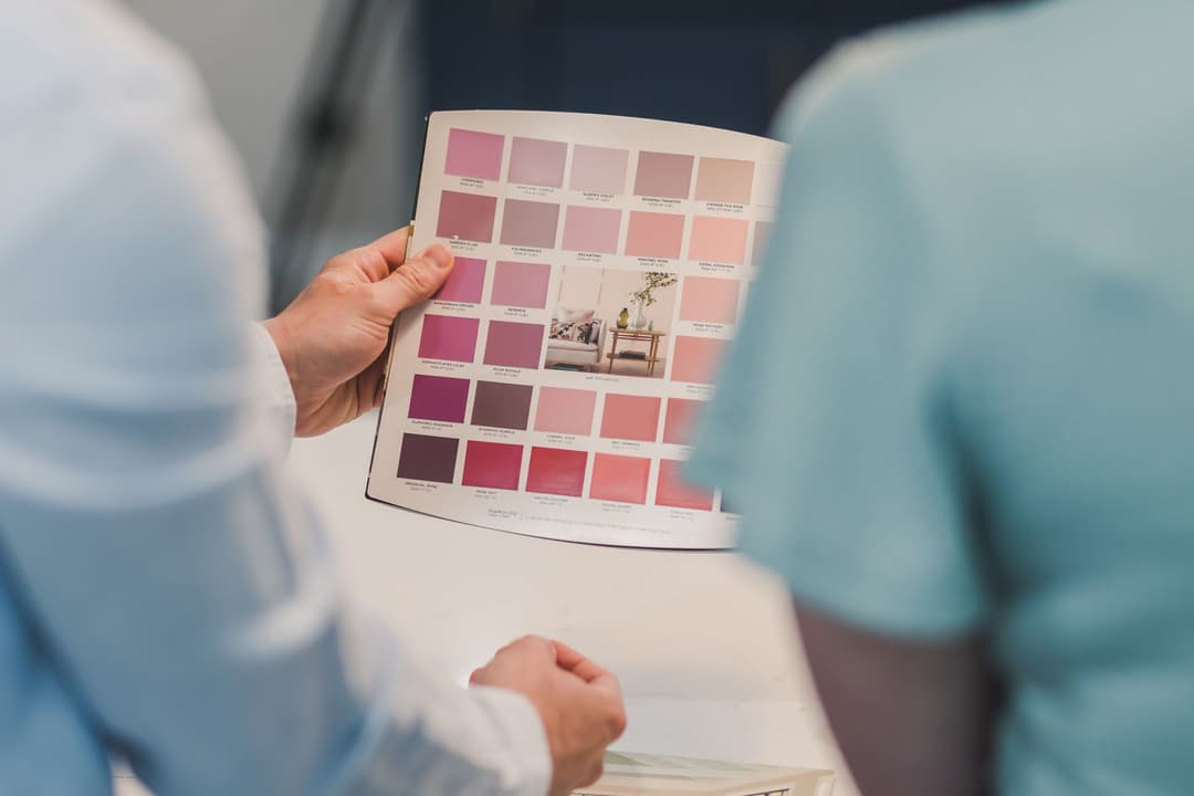 คนกำลังเทียบสีรูปภาพมงคลกับโทนสีผนังห้องนั่งเล่นก่อนตัดสินใจซื้อ