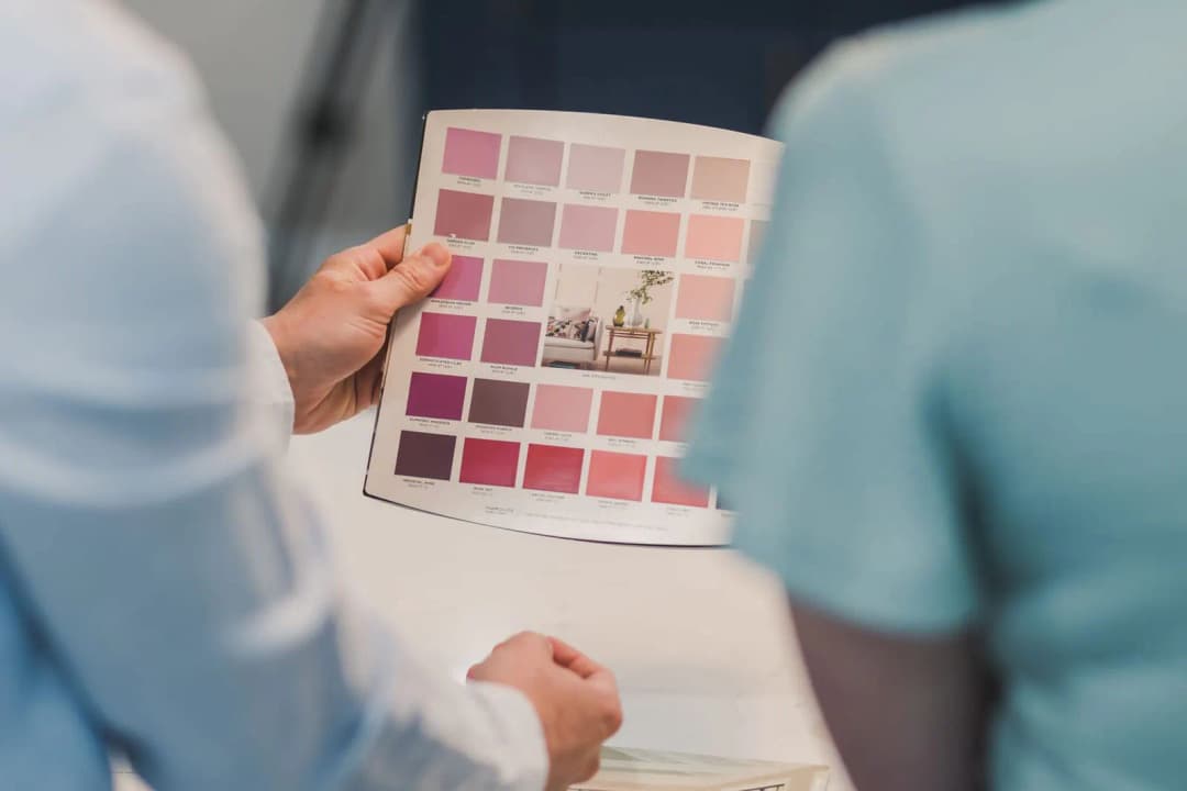 คนกำลังเทียบสีรูปภาพมงคลกับโทนสีผนังห้องนั่งเล่นก่อนตัดสินใจซื้อ