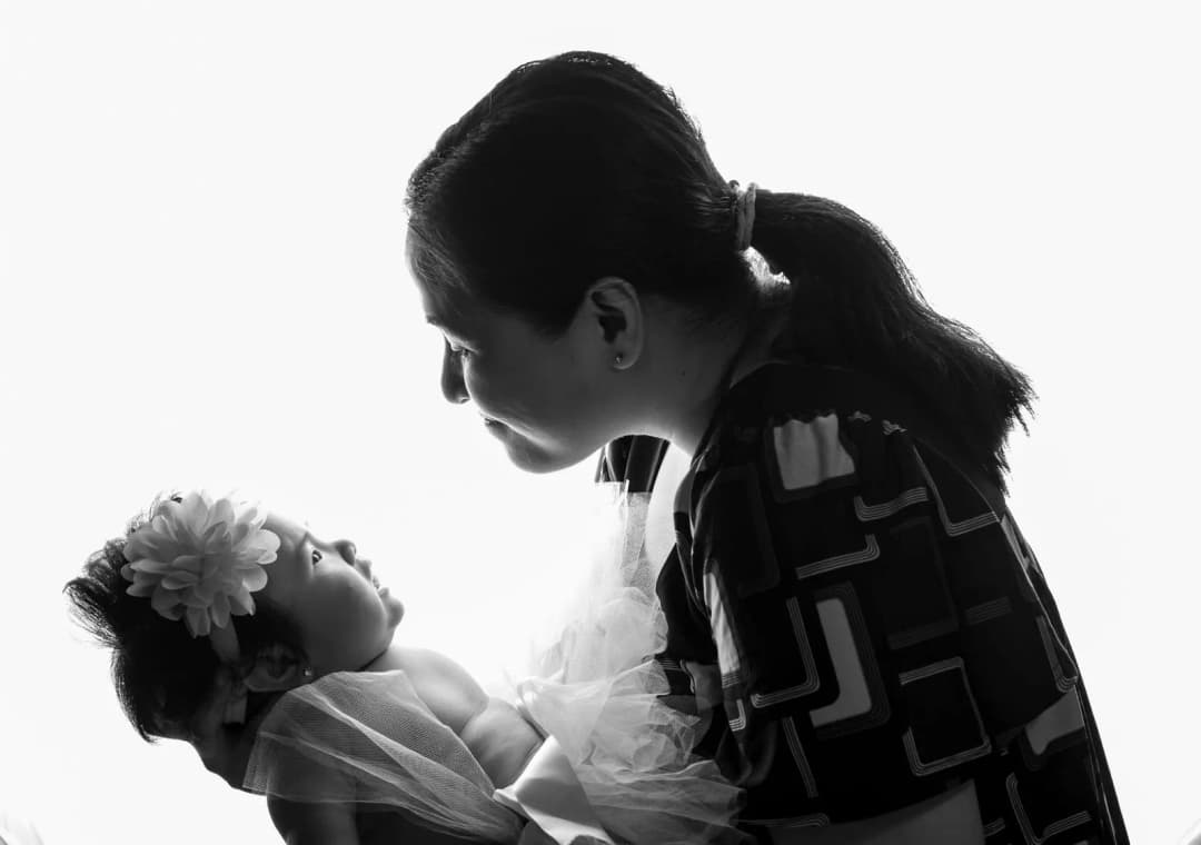 คุณแม่ท้องแก่นั่งจดชื่อลูกสาวลงสมุดโน้ตข้างเปลเด็ก