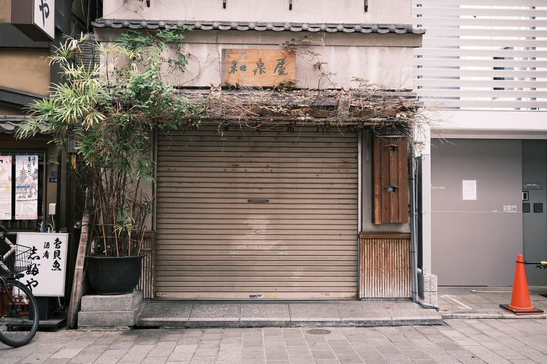 ป้ายปิดร้านถาวรติดอยู่หน้าประตูม้วนร้านค้าที่ปิดกิจการแล้ว