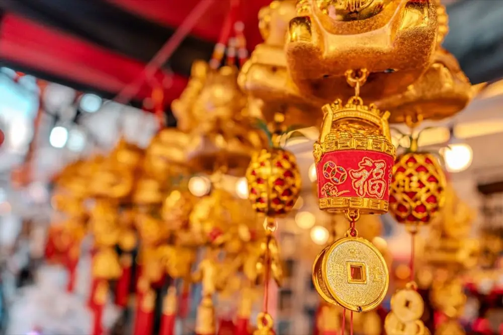 เหรียญโชคจีนสีทองแขวนพวงกุญแจ วางเทียบระหว่างในรถกับกระเป๋าถือ