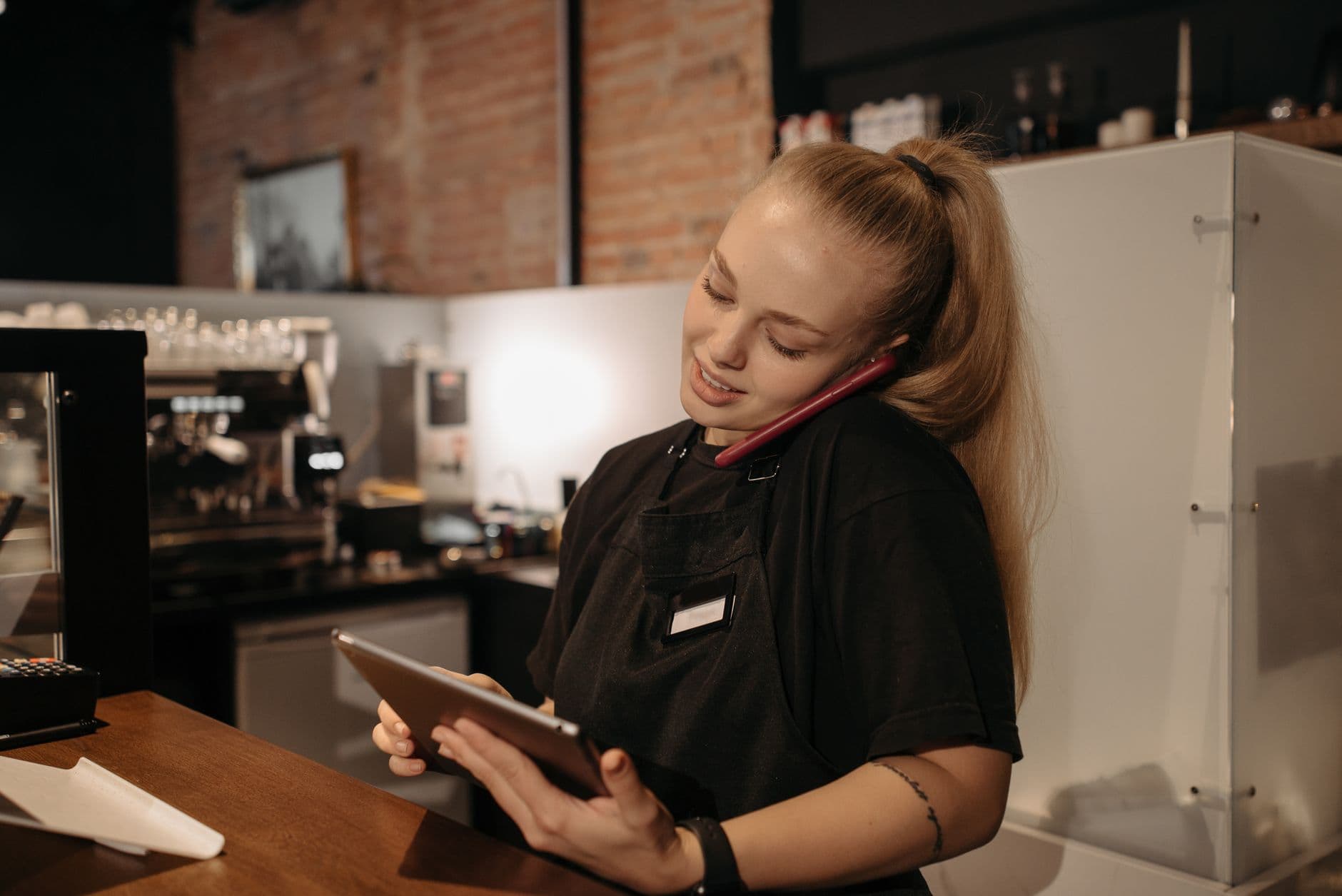 เจ้าของร้านถือโทรศัพท์รับสายลูกค้าอยู่หลังเคาน์เตอร์ร้าน