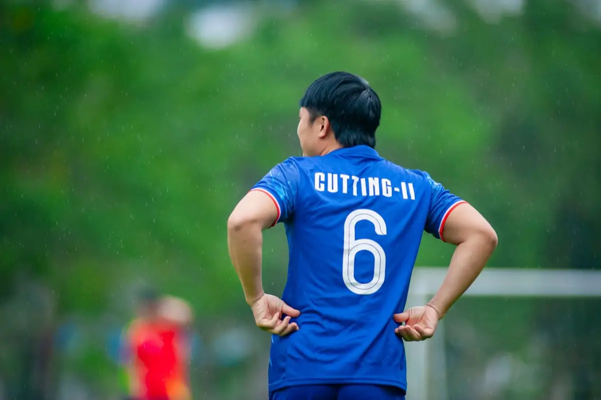 นักกีฬาสวมเสื้อทีมสีเข้มยืนอยู่ในสนามแข่งขันนอกบ้าน