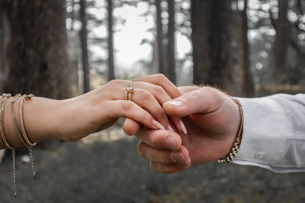 มือคู่รักสวมกำไลข้อมือคนละสี เงินและทอง วางประกบกัน