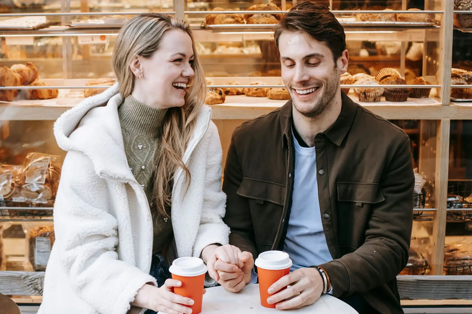 คู่หนุ่มสาวนั่งคุยกันยิ้มแย้มในร้านกาแฟระหว่างเดตแรก