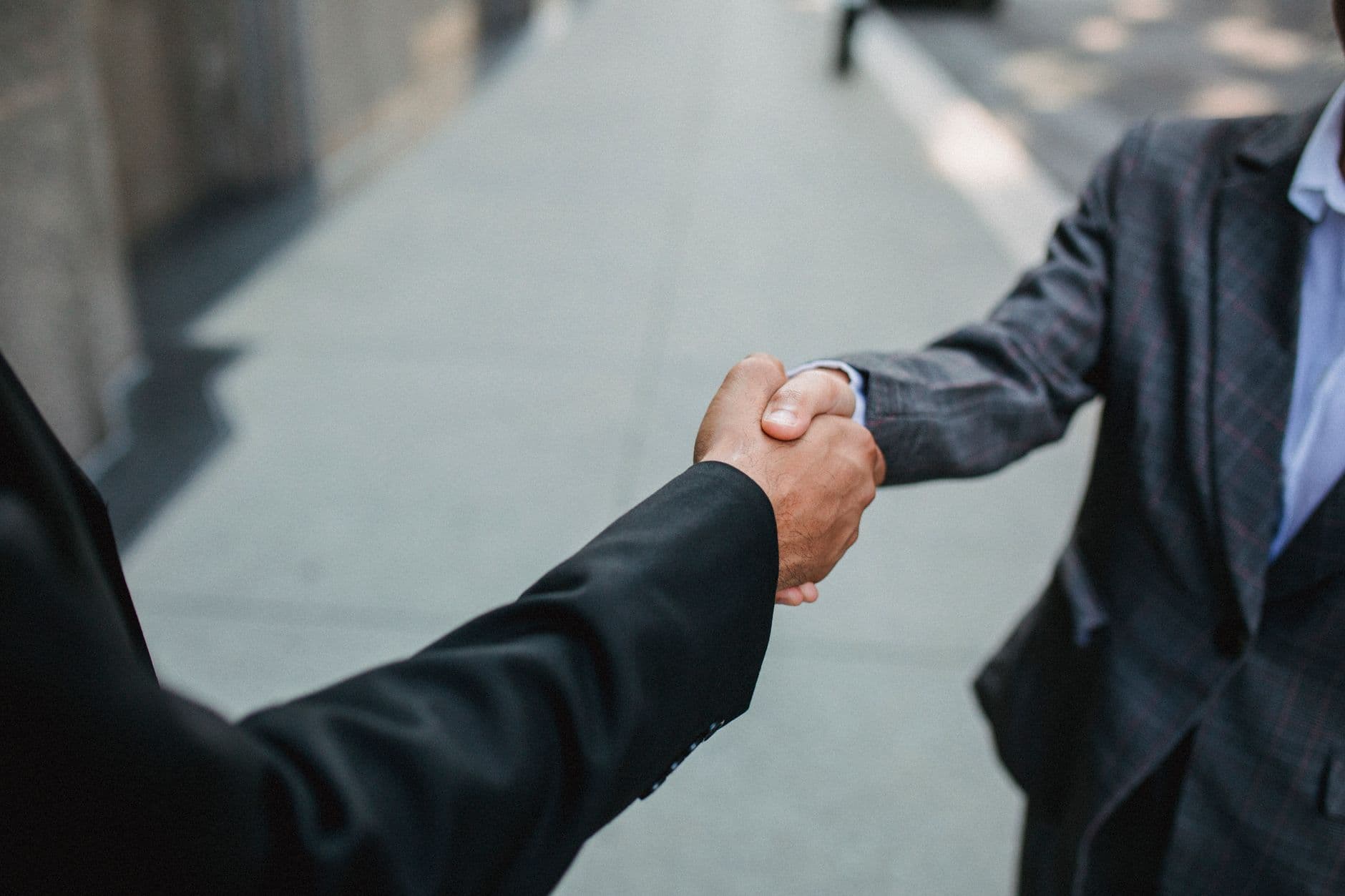 สองฝ่ายจับมือกันหลังเซ็นเอกสารสัญญาแฟรนไชส์บนโต๊ะทำงาน