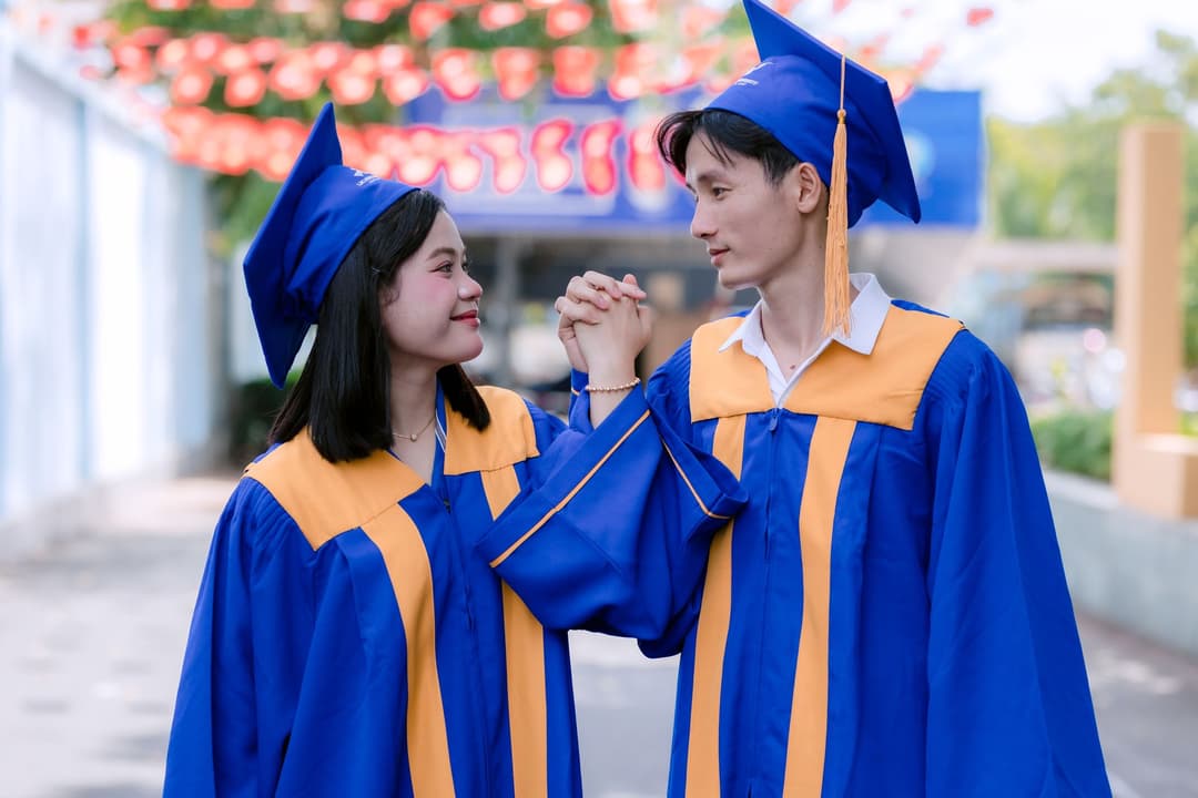 บัณฑิตสวมชุดครุยถ่ายรูปกับครอบครัวหน้าหอประชุมมหาวิทยาลัย