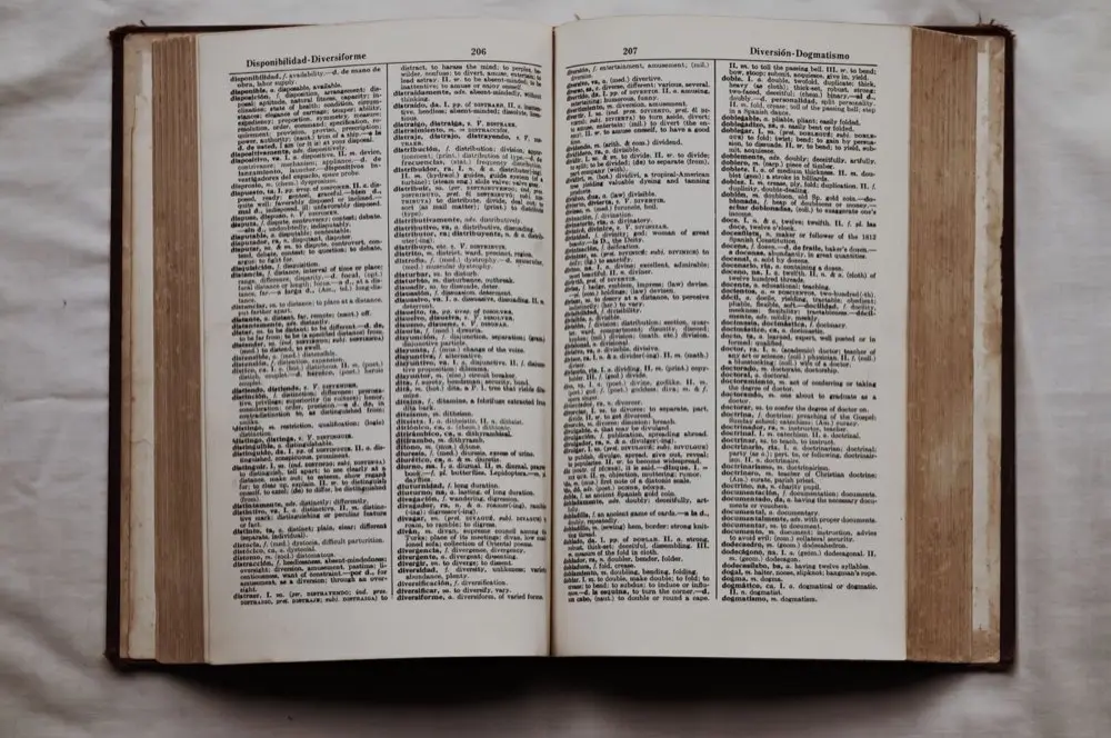 หนังสือพจนานุกรมไทยเปิดอยู่บนโต๊ะแสดงความหมายของคำ