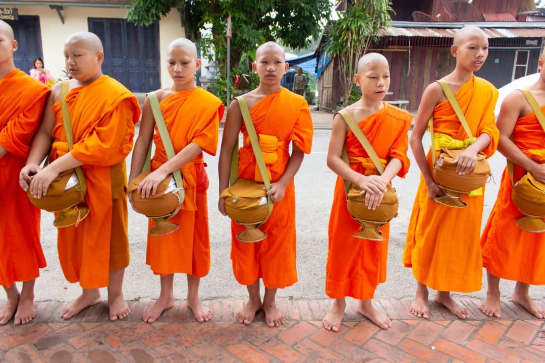 พระสงฆ์รับบิณฑบาตในพิธีทำบุญบ้านพร้อมเจ้าของบ้านนั่งพนมมือ