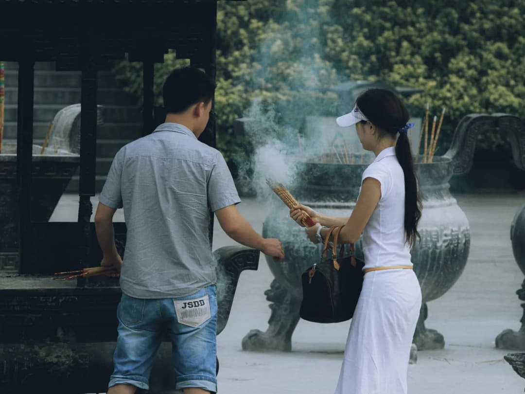 มือจุดธูปสามดอกด้วยไฟแช็กหน้ากระถางธูปในบ้าน