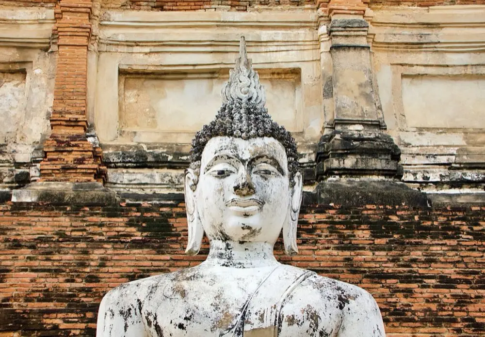 พระเครื่ององค์เก่าสีเข้มวางอยู่บนผ้าไหมโบราณ