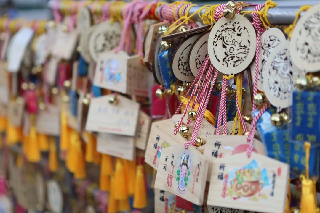 เครื่องรางโอมาโมริหลายแบบหลายสีวางเปรียบเทียบกันบนโต๊ะไม้