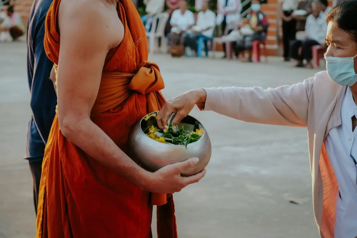 พระสงฆ์รับผ้าไตรจากญาติโยมในพิธีทอดผ้าไหว้พระที่วัด