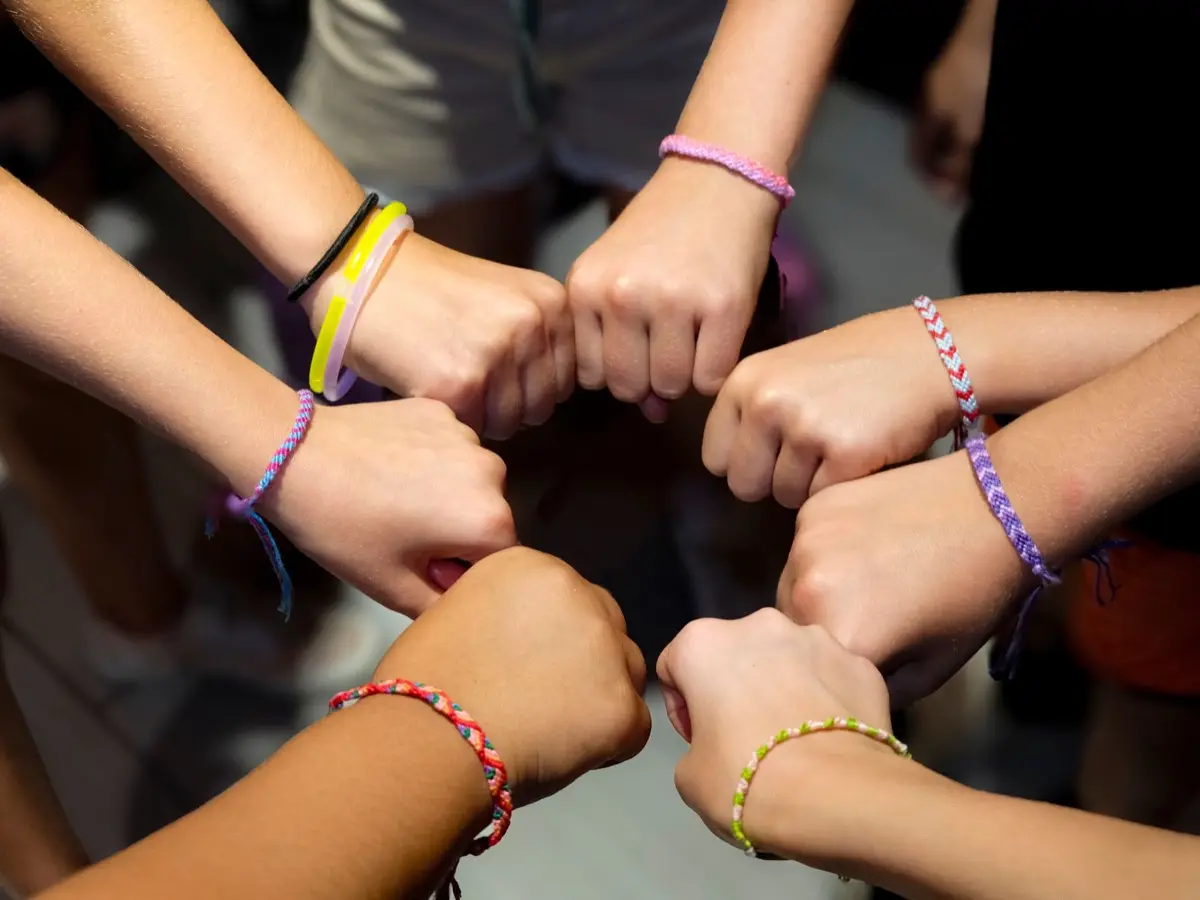 กำไลเพื่อนซี้ถักด้ายสีสันสวมอยู่บนข้อมือสองข้างที่ประกบกัน