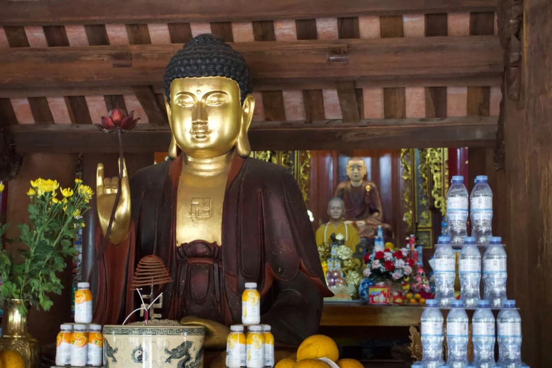 ดอกบัวสดวางอยู่บนพานทองเหลืองหน้าพระพุทธรูปในบรรยากาศอบอุ่น