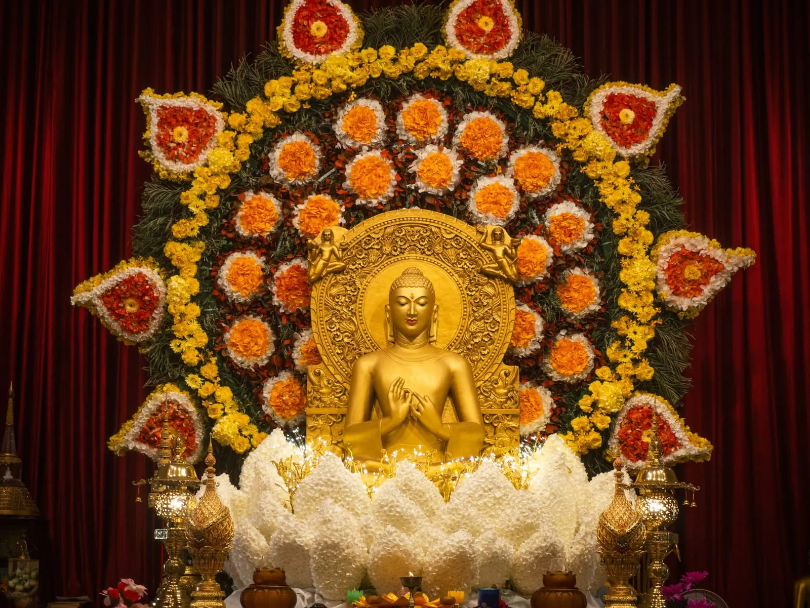 ดอกบัวและดอกไม้ถวายพระวางอยู่บนพานหน้าพระพุทธรูปในบ้าน