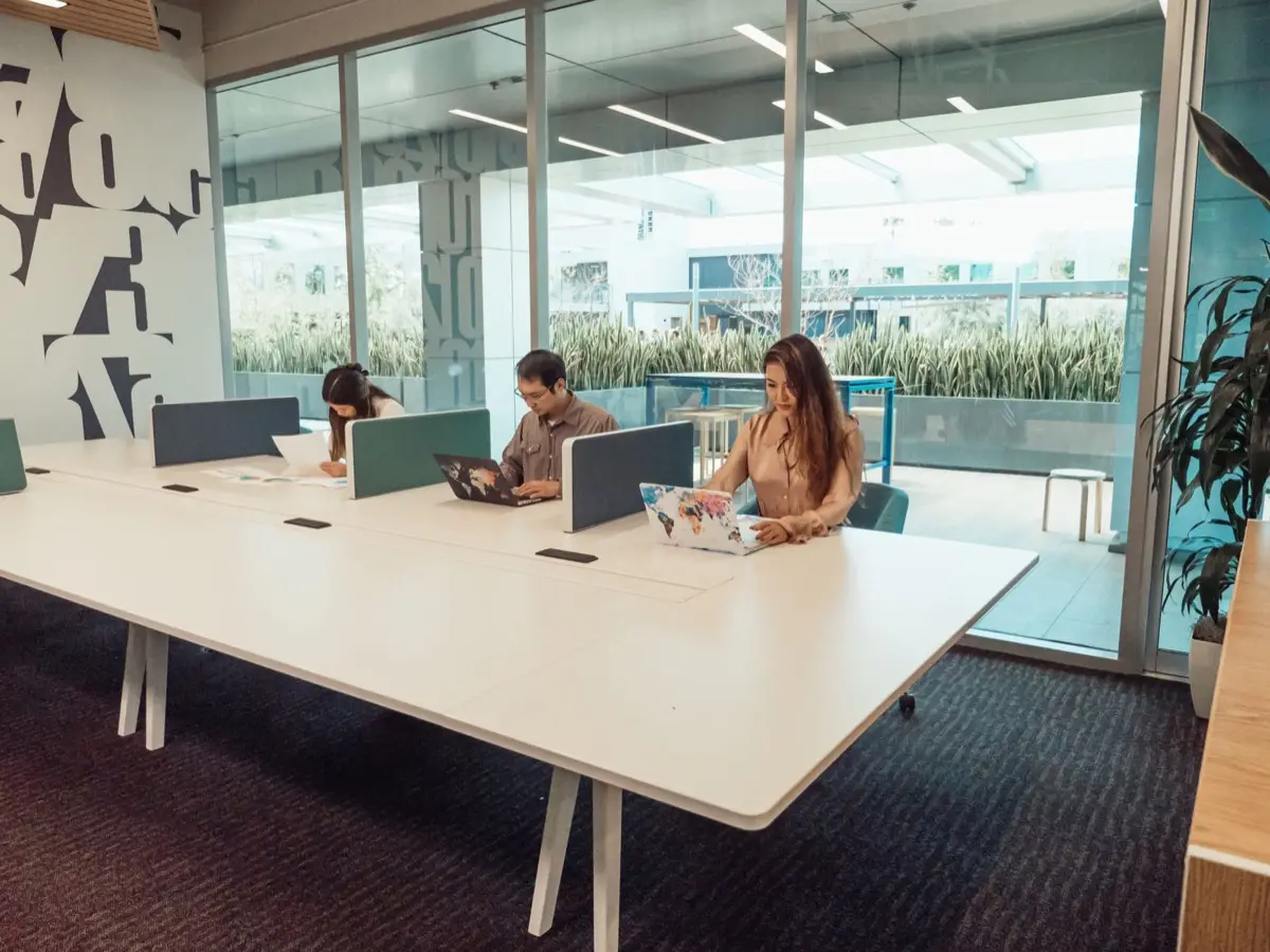 พื้นที่ co-working space ที่มีโต๊ะทำงานร่วมและคนนั่งทำงานกับโน้ตบุ๊ก