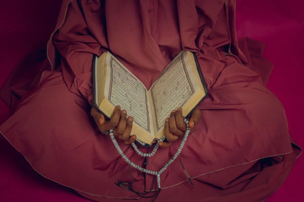 หนังสือสวดมนต์เปิดอยู่บนโต๊ะข้างเทียนจุดสว่าง บรรยากาศสงบยามเย็น