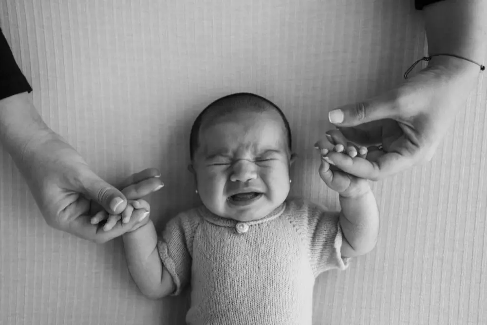 พ่อแม่อุ้มทารกแรกเกิดจับมือเล็ก ๆ ของลูก