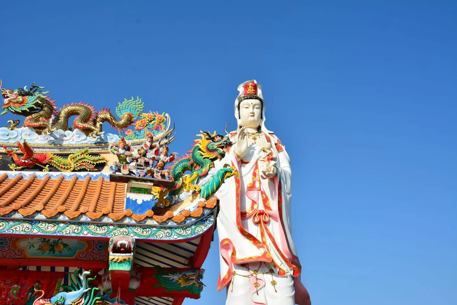 รูปปั้นเทพีหลายองค์เรียงกันในลานวัดไทย สื่อถึงการเปรียบเทียบความเชื่อ