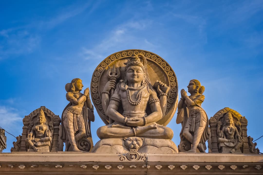 รูปปั้นหินพระศิวะโบราณตั้งอยู่ในเทวสถานที่มีแสงแดดส่องผ่าน
