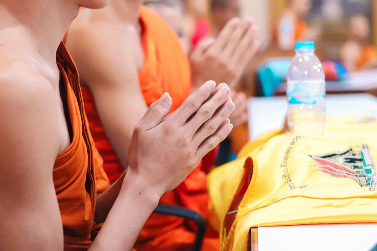 คนหลากหลายวัยกำลังนั่งพนมมือไหว้อยู่หน้าหิ้งพระในบ้าน