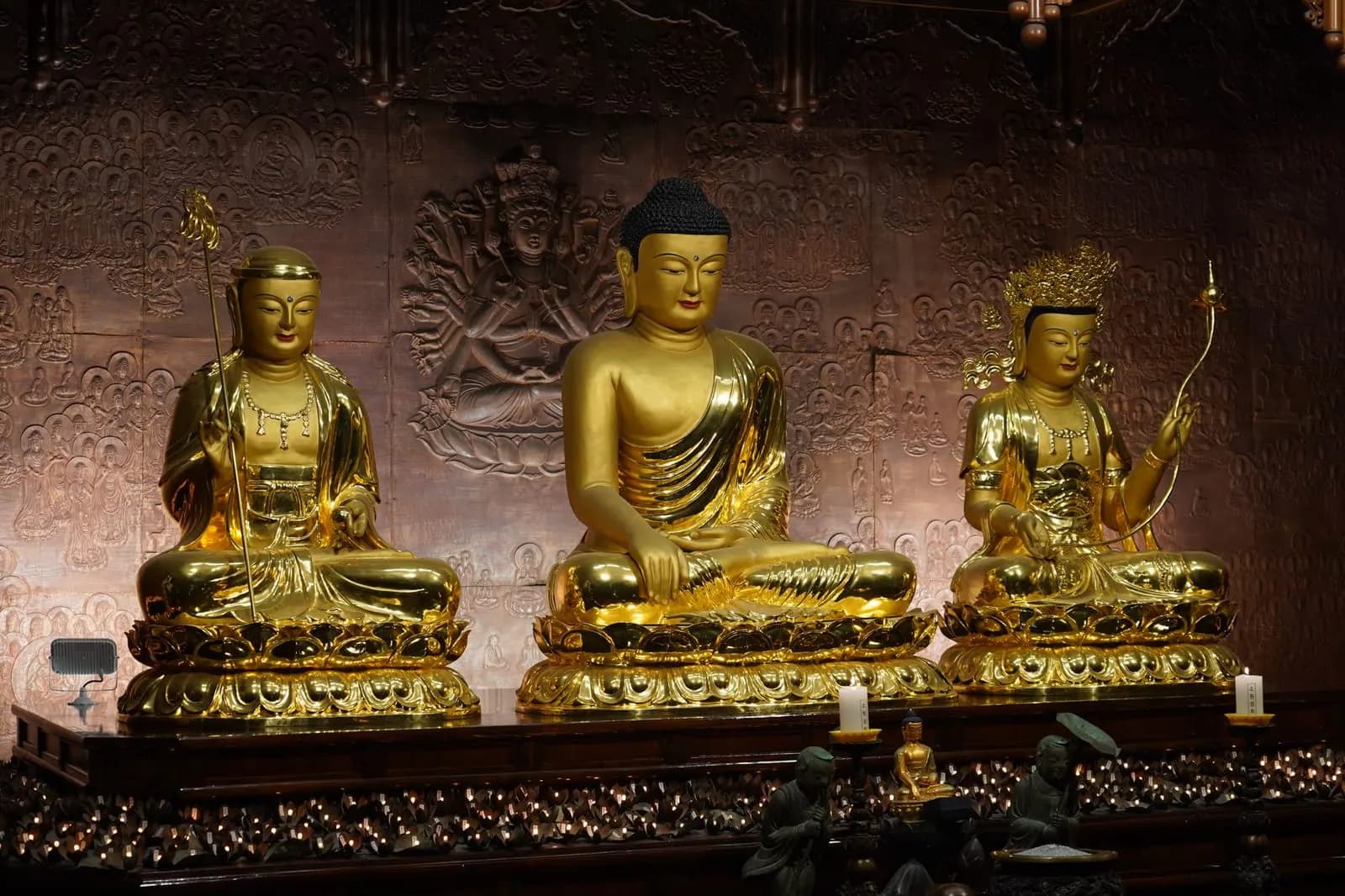 คนกำลังจัดวางพระพุทธรูปและของบูชาบนชั้นวางไม้ในห้องคอนโดขนาดเล็ก