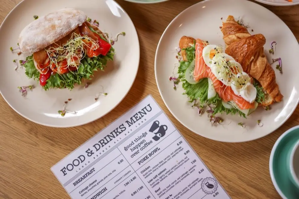 เมนูอาหารเปิดวางอยู่บนโต๊ะร้านอาหารพร้อมจานอาหารข้างเคียง