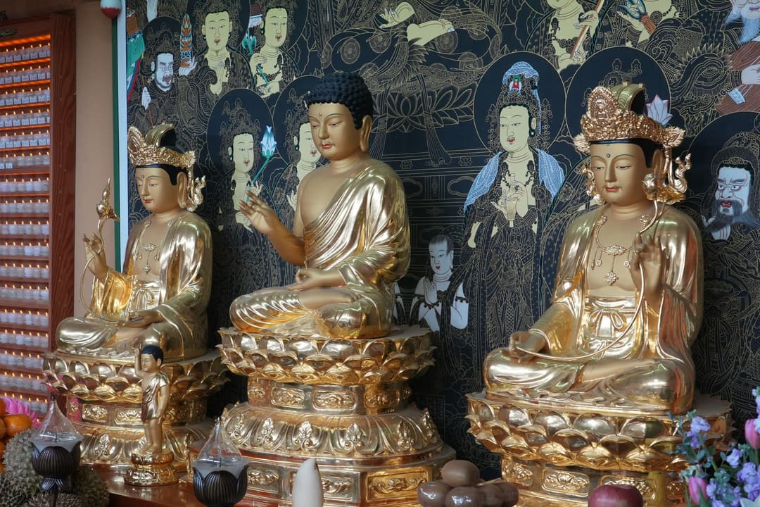 รูปปั้นพระพุทธรูปหลายปางเรียงเทียบกันในศาลเจ้า
