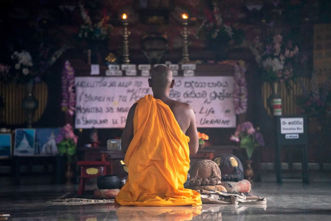 ผู้หญิงกำลังจุดธูปตั้งจิตอธิษฐานหน้ารูปปั้นพระสังกัจจายน์