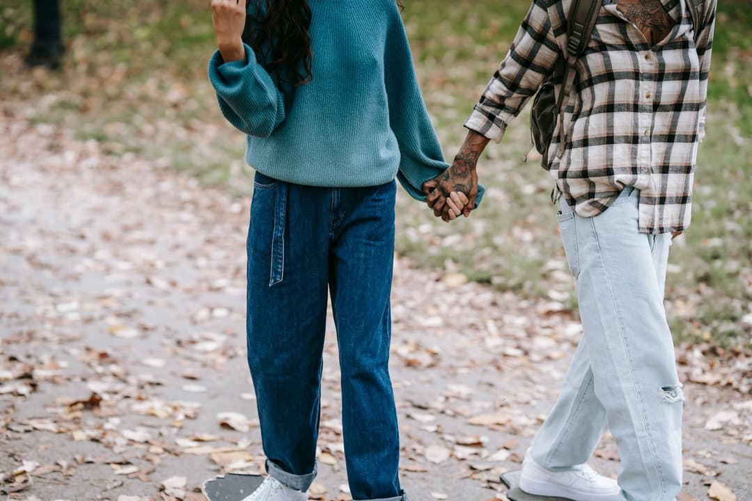 คู่รักจับมือกันเดินในสวนสาธารณะยามใบไม้ร่วง บรรยากาศฤดูกันยายนอบอุ่น