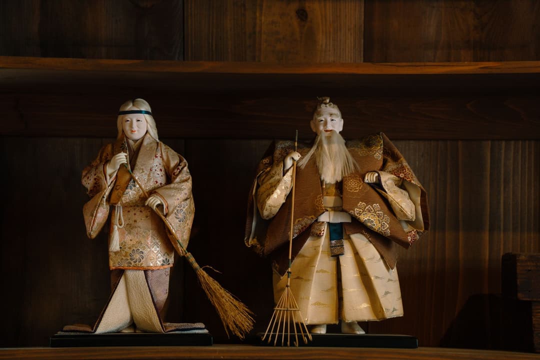 ตุ๊กตาคู่ชายหญิงวางคู่กันบนหิ้งไม้เล็กในห้องนอน