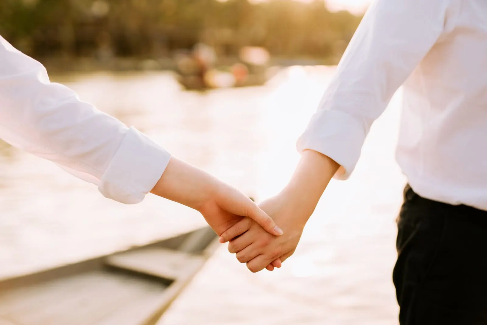 คู่รักจับมือกันท่ามกลางแสงอาทิตย์อ่อน ๆ ยามเย็น