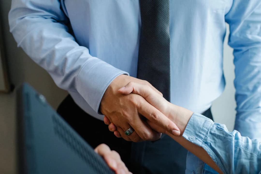 คนสองคนยืนจับมือแนะนำตัวกันในบรรยากาศเป็นกันเอง